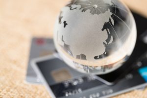 A glass globe sits on top of a credit card, displaying a futuristic fusion of technology.