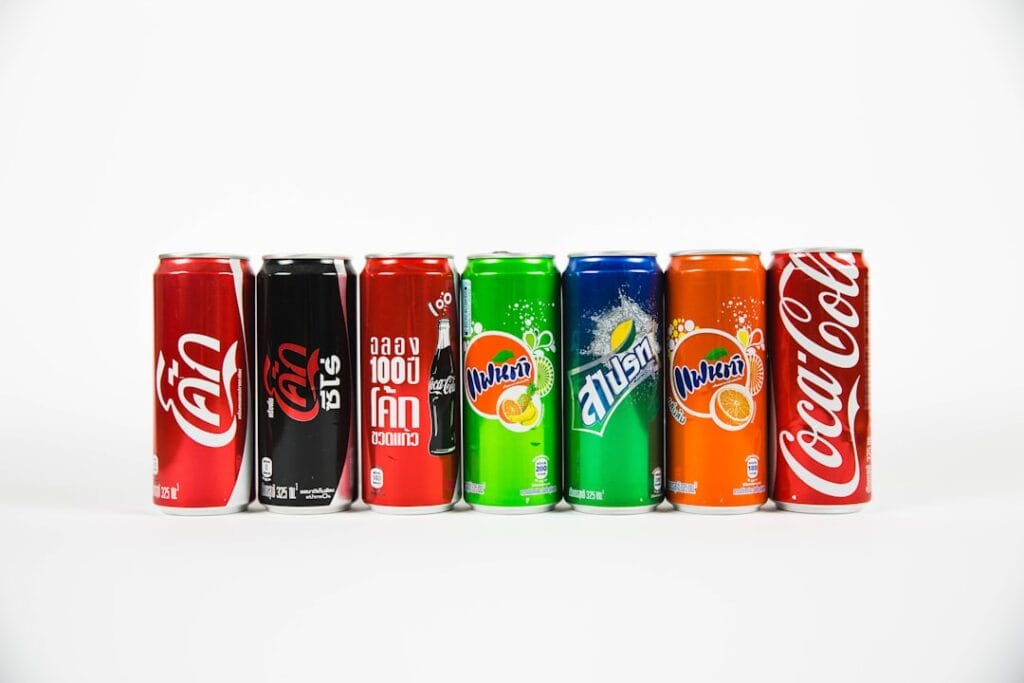 A lineup of various soft drink cans from different brands displayed against a white background.